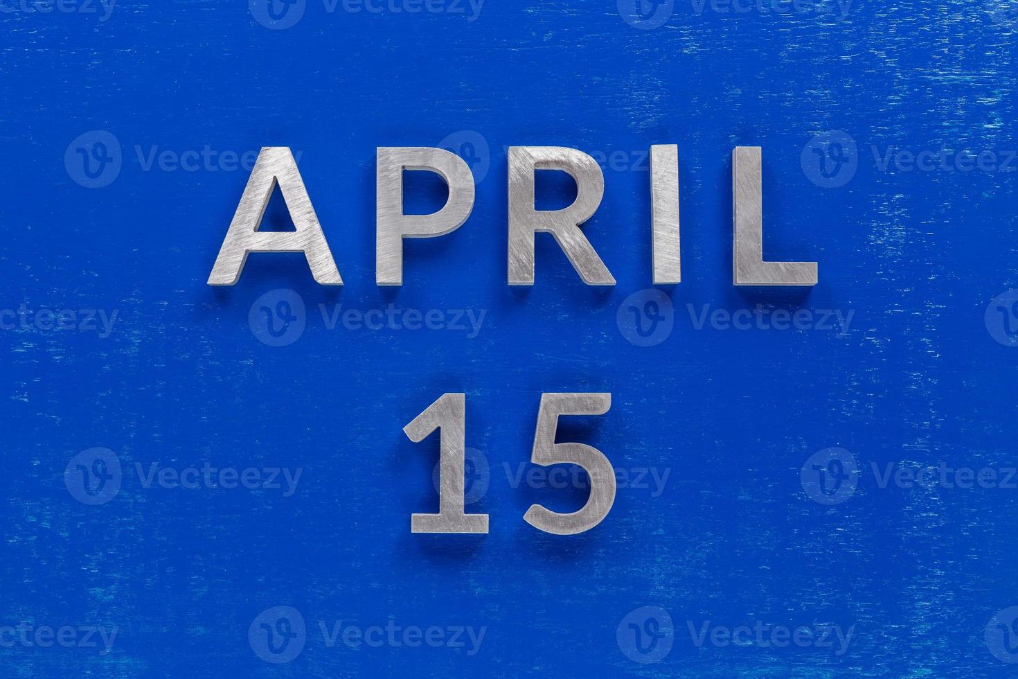 the words april 15 layed on blue painted board with thick silver metal aphabet characters photo