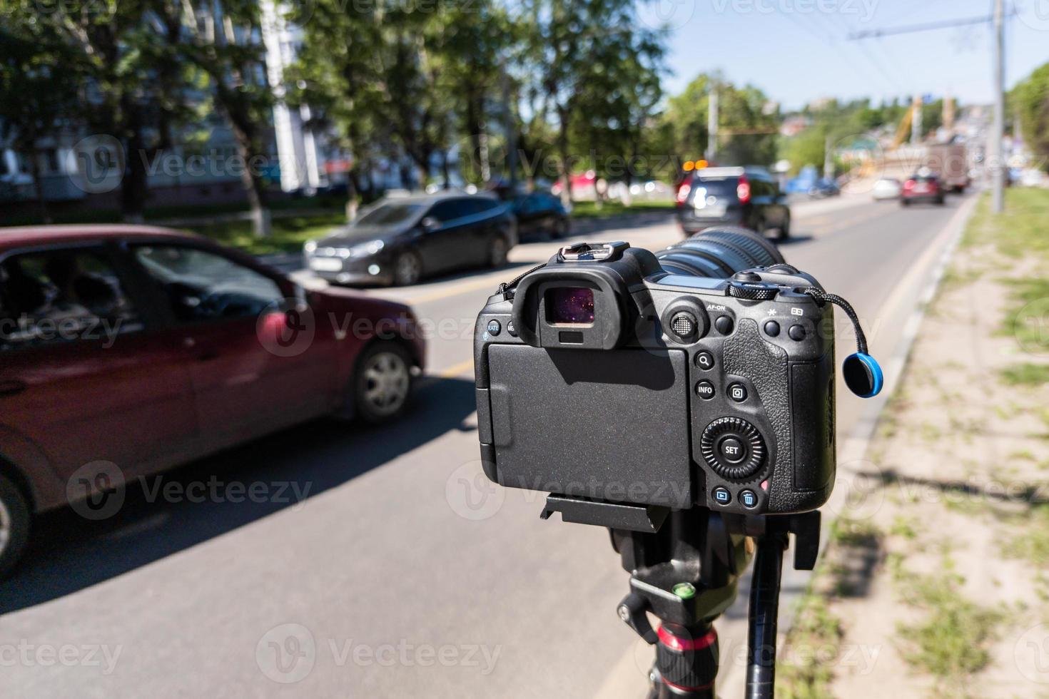 modern black professional mirrorless camera on tripod or monopod shooting city car traffic at summer day photo