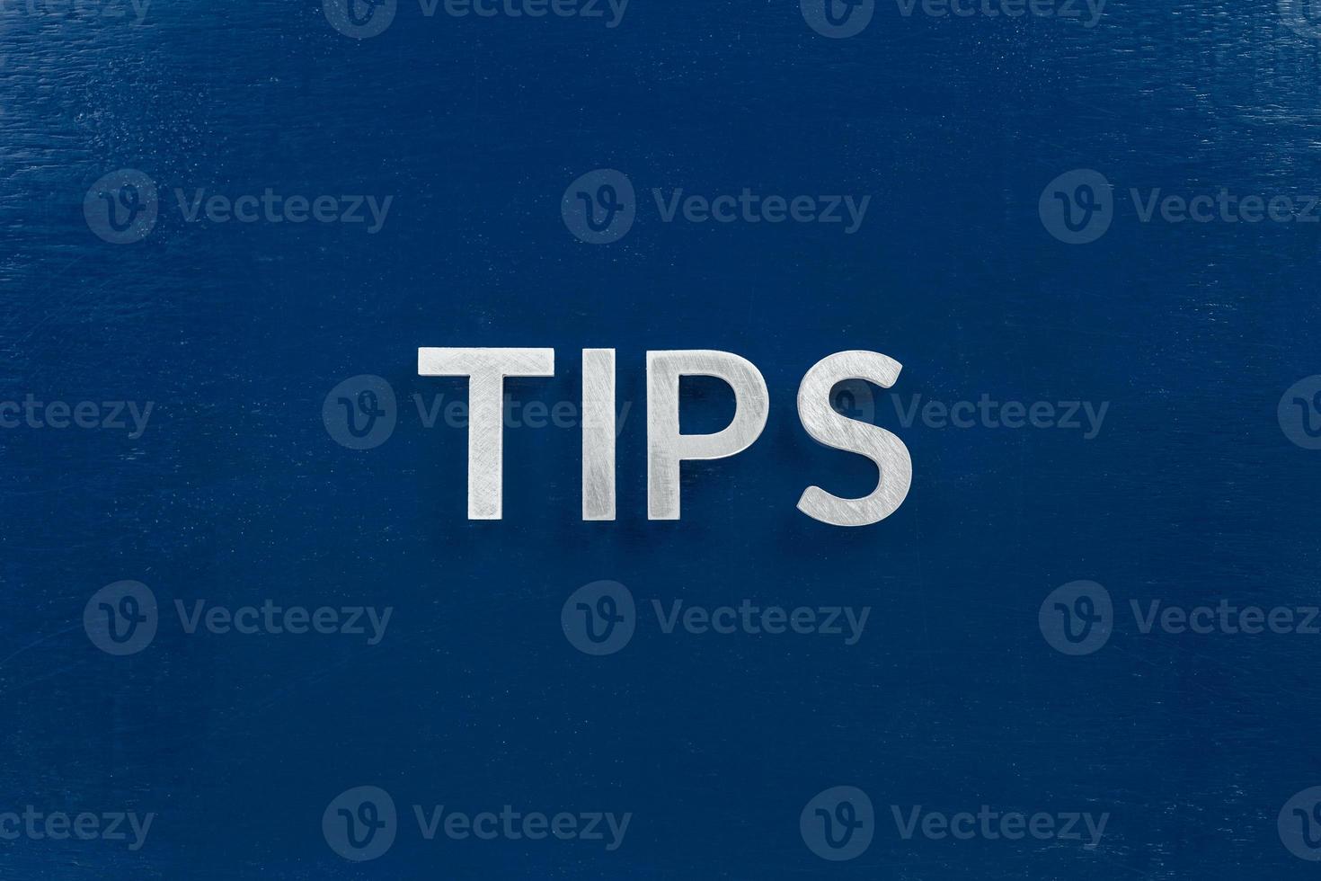 the word tips laid with silver letters on blue color surface photo