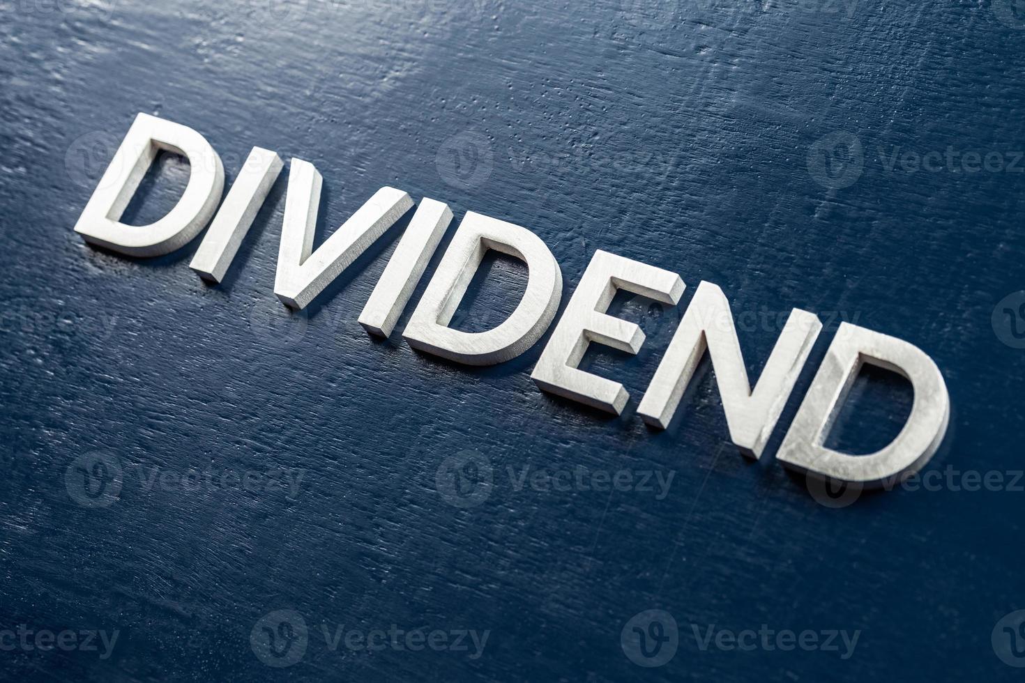the word dividend laid by volumetric silver metal letters on gloss painted board background with selective focus photo