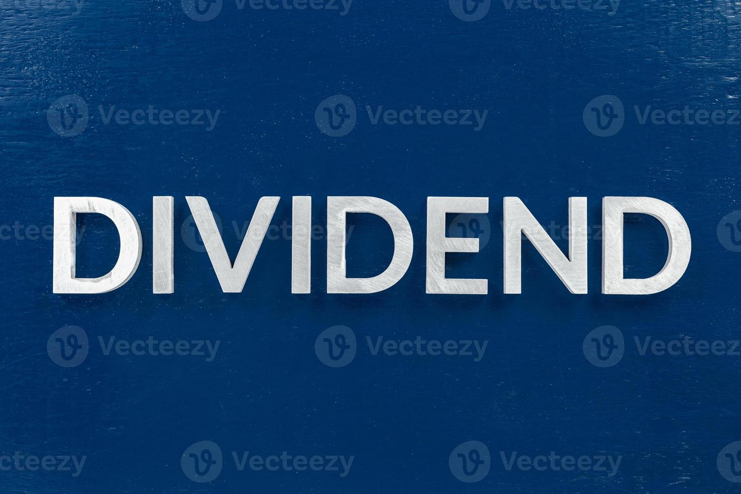 the word dividend laid with brushed metal letters on dark blue background photo