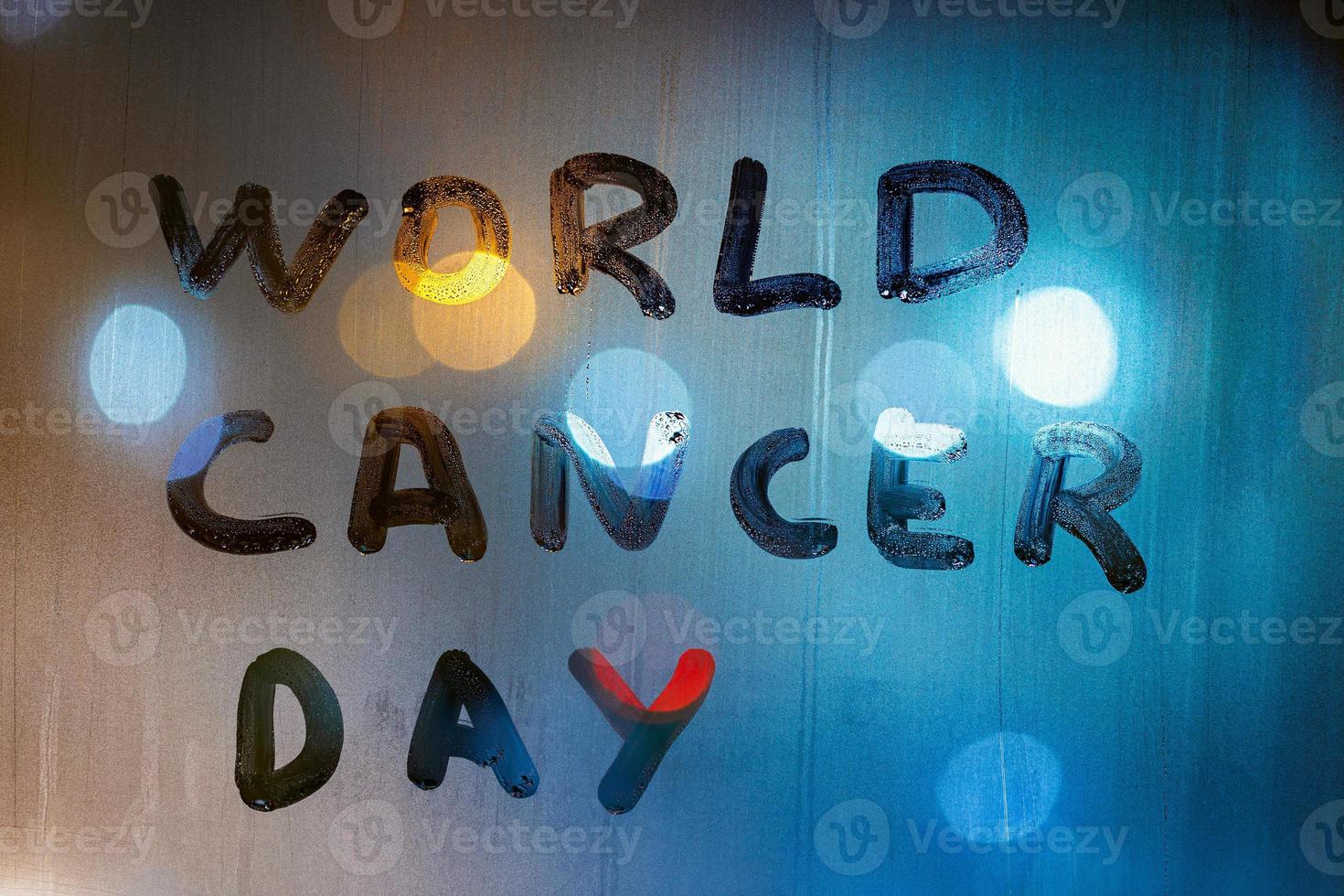 the words world cancer day handwritten on night wet glass - close-up with background blur photo