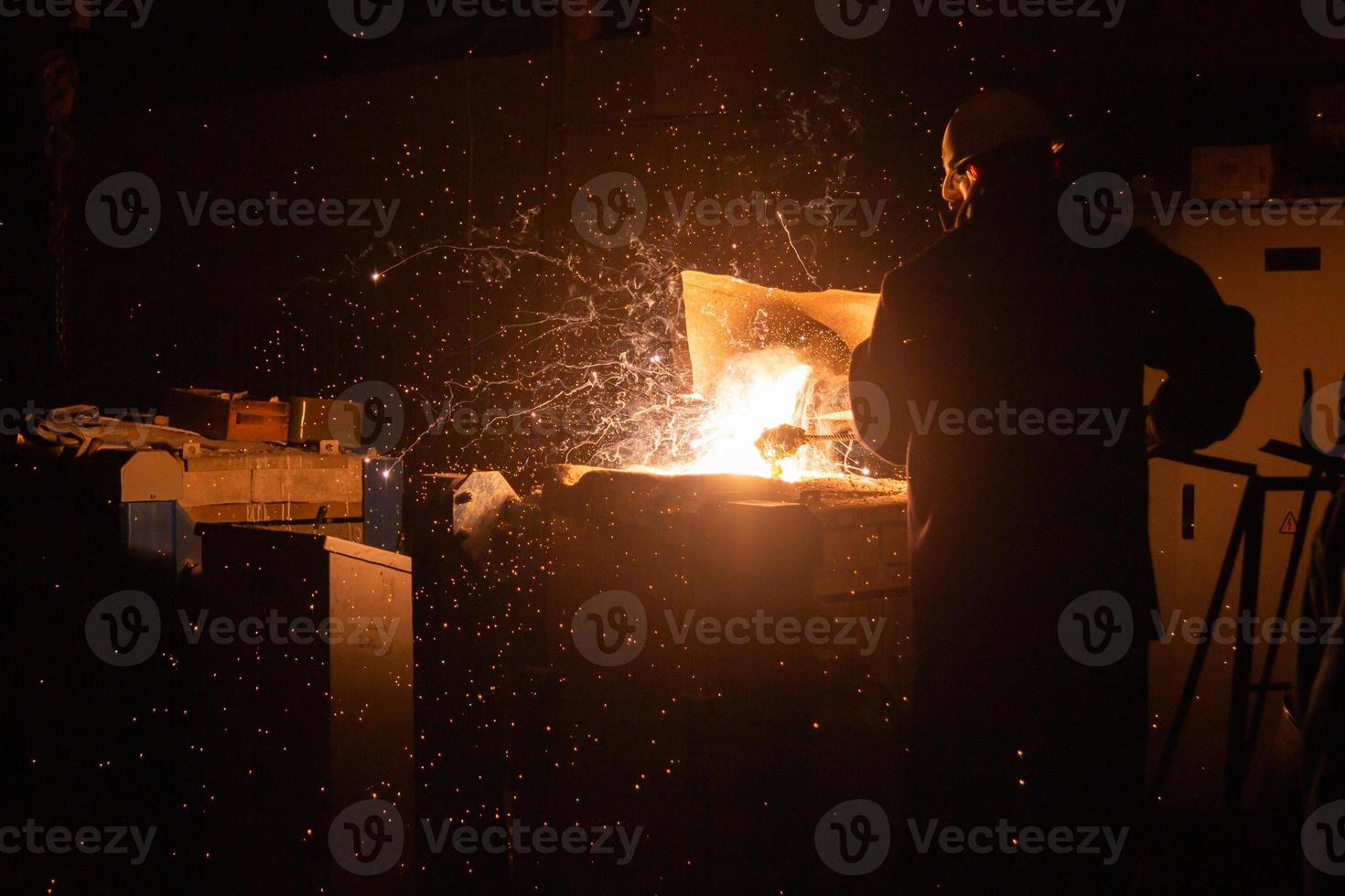 trabajador siderúrgico quitando escoria del horno de acero con chispas y escape de humo foto