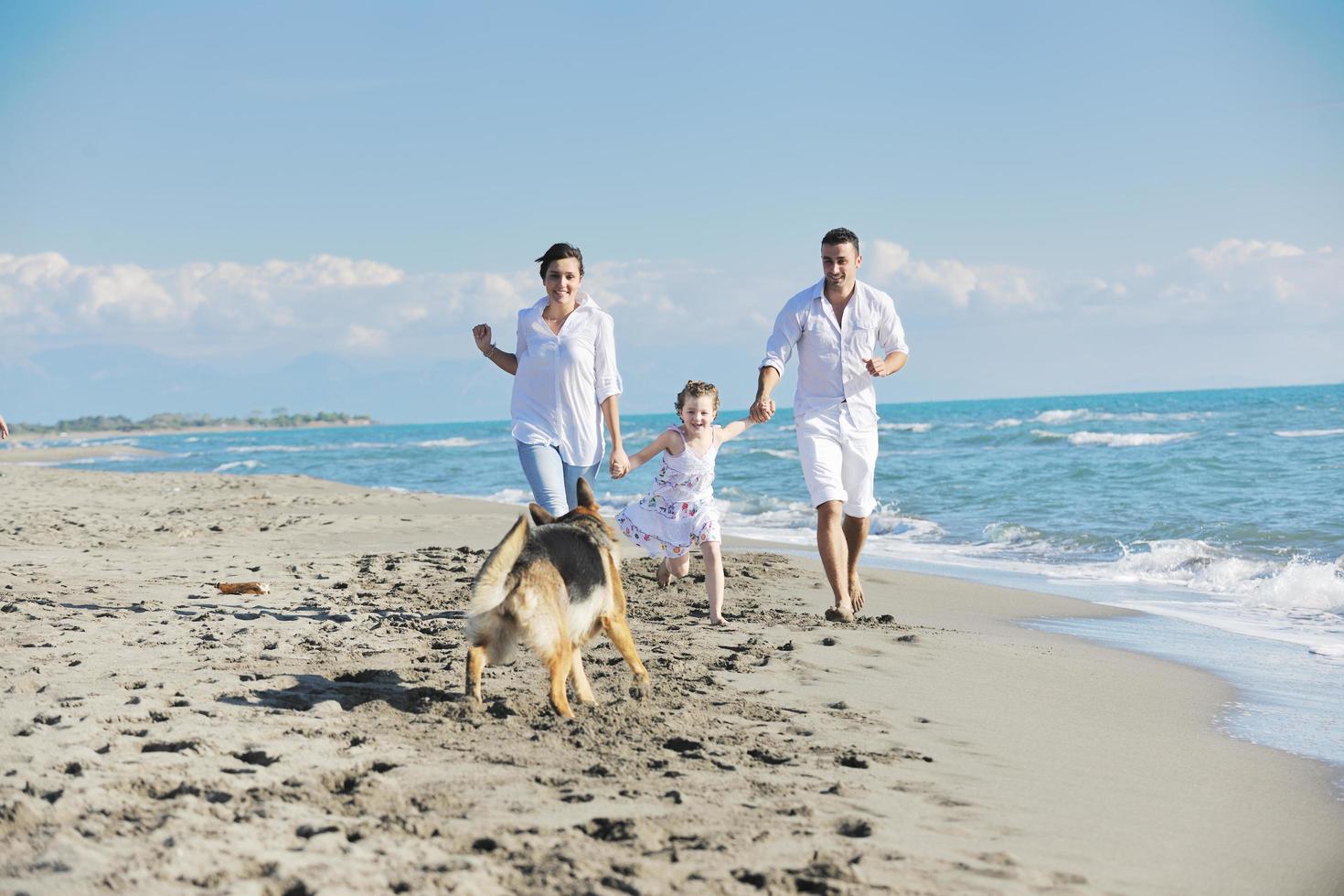 familia feliz jugando con el perro en la playa foto