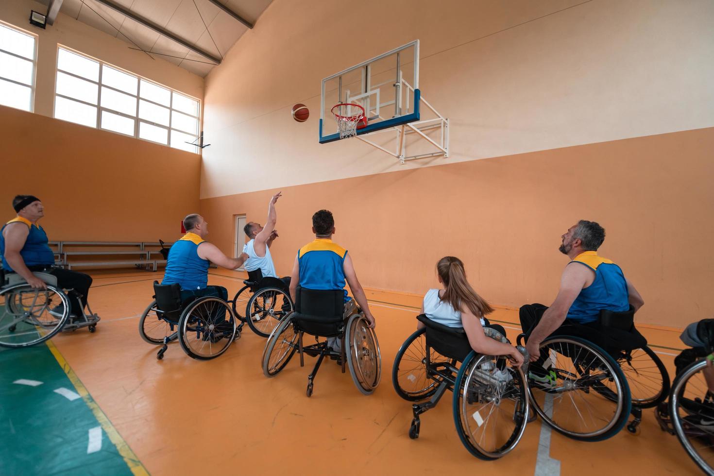 Disabled War veterans mixed race and age basketball teams in wheelchairs playing a training match in a sports gym hall. Handicapped people rehabilitation and inclusion concept photo