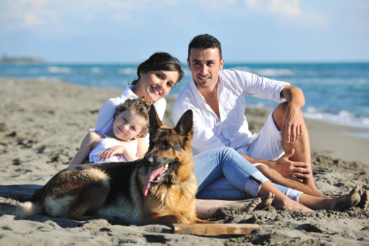 familia feliz jugando con el perro en la playa foto