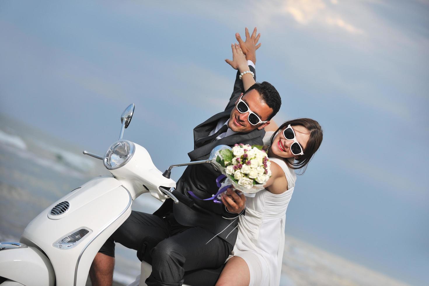 just married couple on the beach ride white scooter photo
