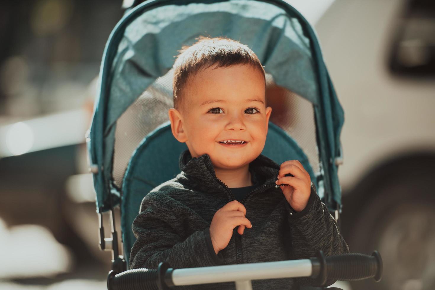 Sweet baby boy in a stroller bicycle outdoors. Little child in a pram. Infant kid in a pushchair. Spring walks with kids. photo