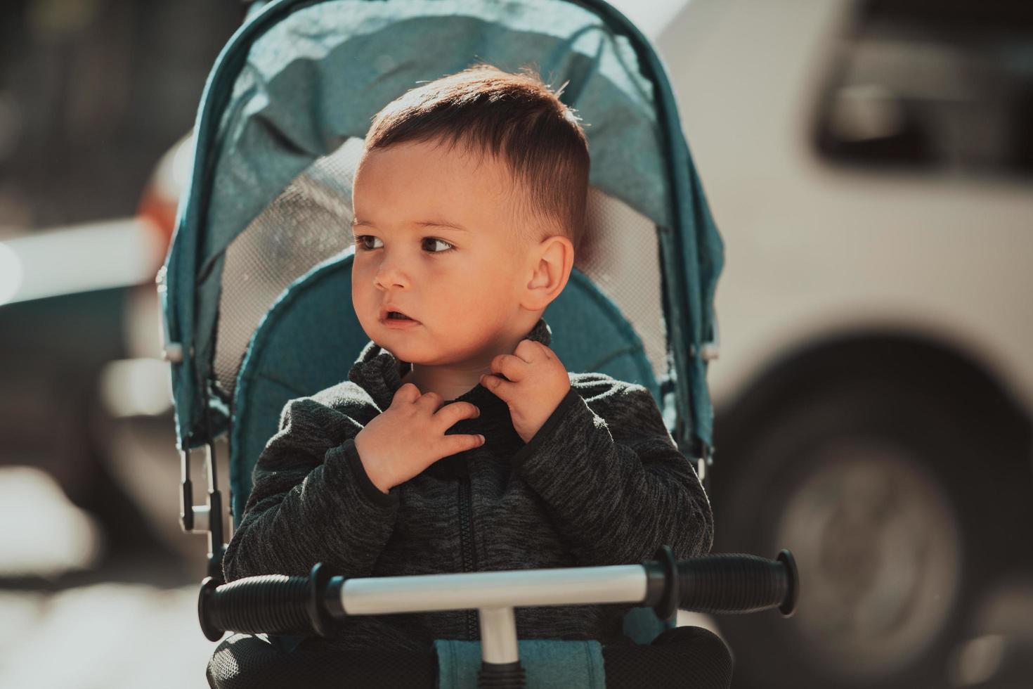 Sweet baby boy in a stroller bicycle outdoors. Little child in a pram. Infant kid in a pushchair. Spring walks with kids. photo