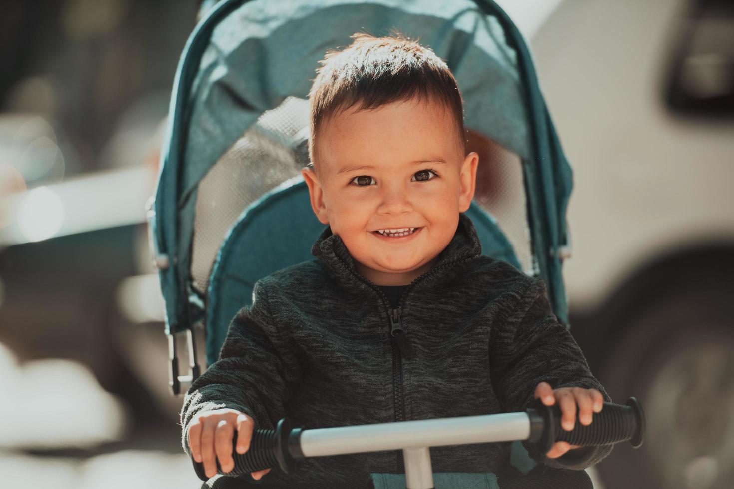 Sweet baby boy in a stroller bicycle outdoors. Little child in a pram. Infant kid in a pushchair. Spring walks with kids. photo