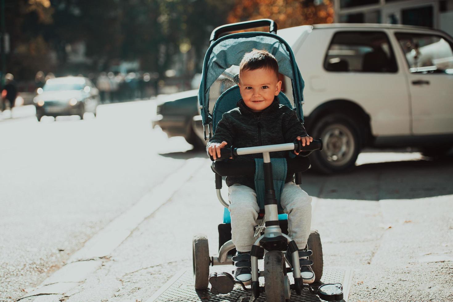 Sweet baby boy in a stroller bicycle outdoors. Little child in a pram. Infant kid in a pushchair. Spring walks with kids. photo