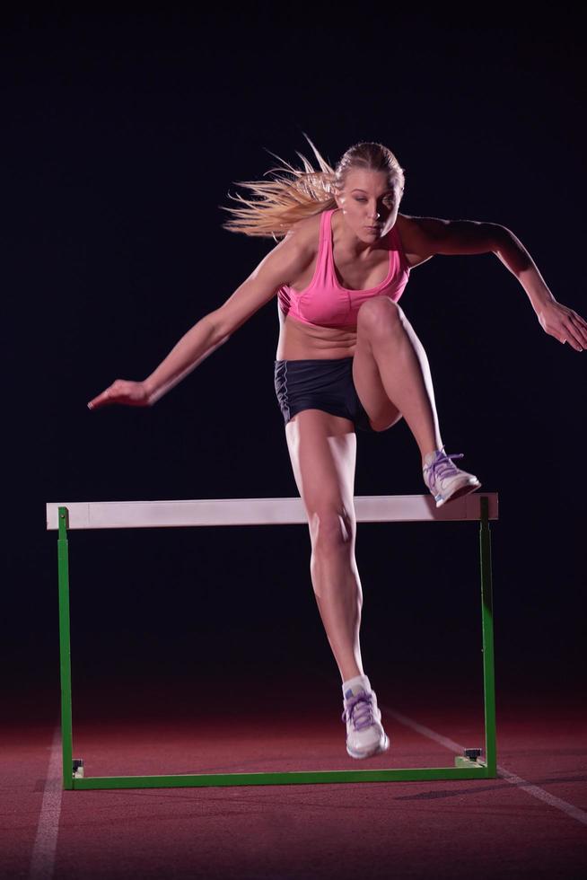 mujer atleta saltando sobre obstáculos foto