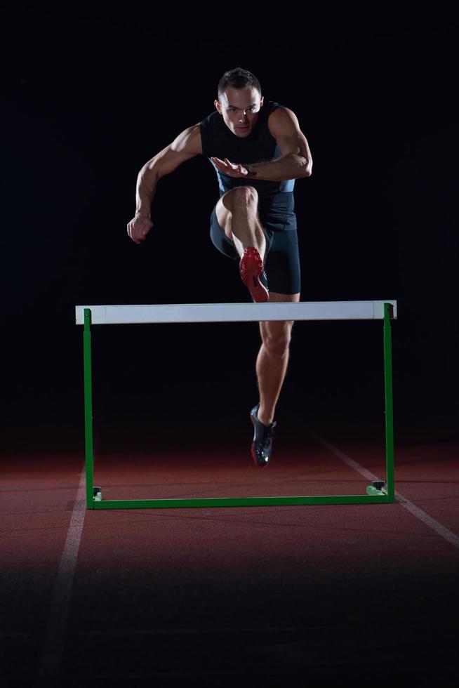 athlete jumping over a hurdles photo