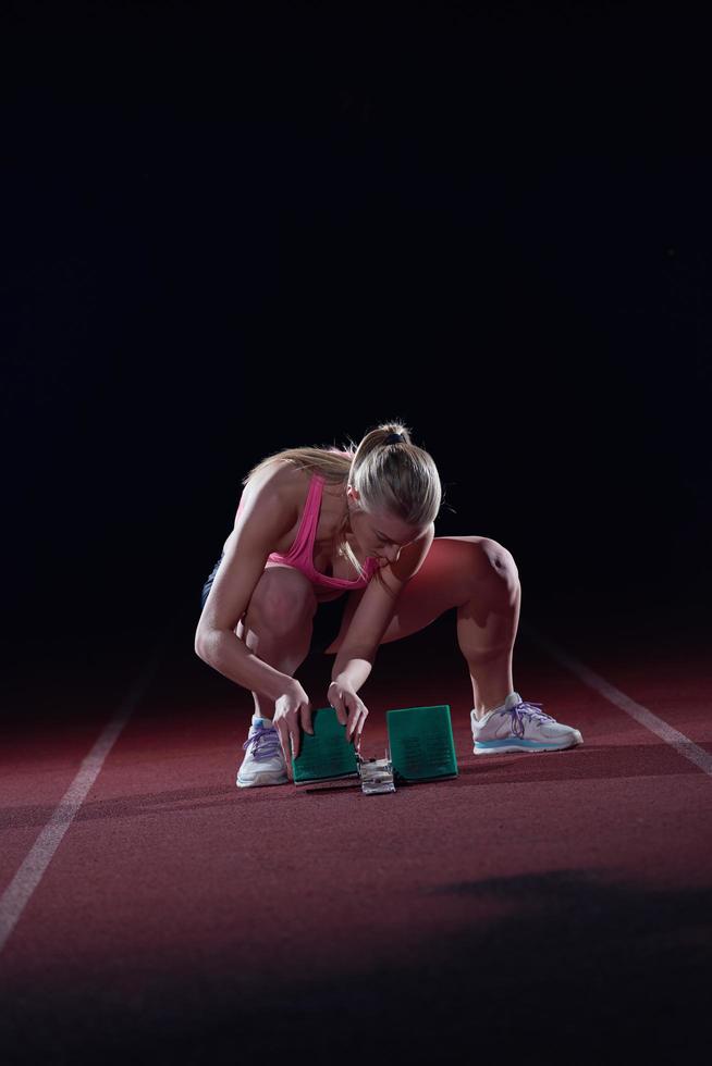 woman  sprinter leaving starting blocks photo