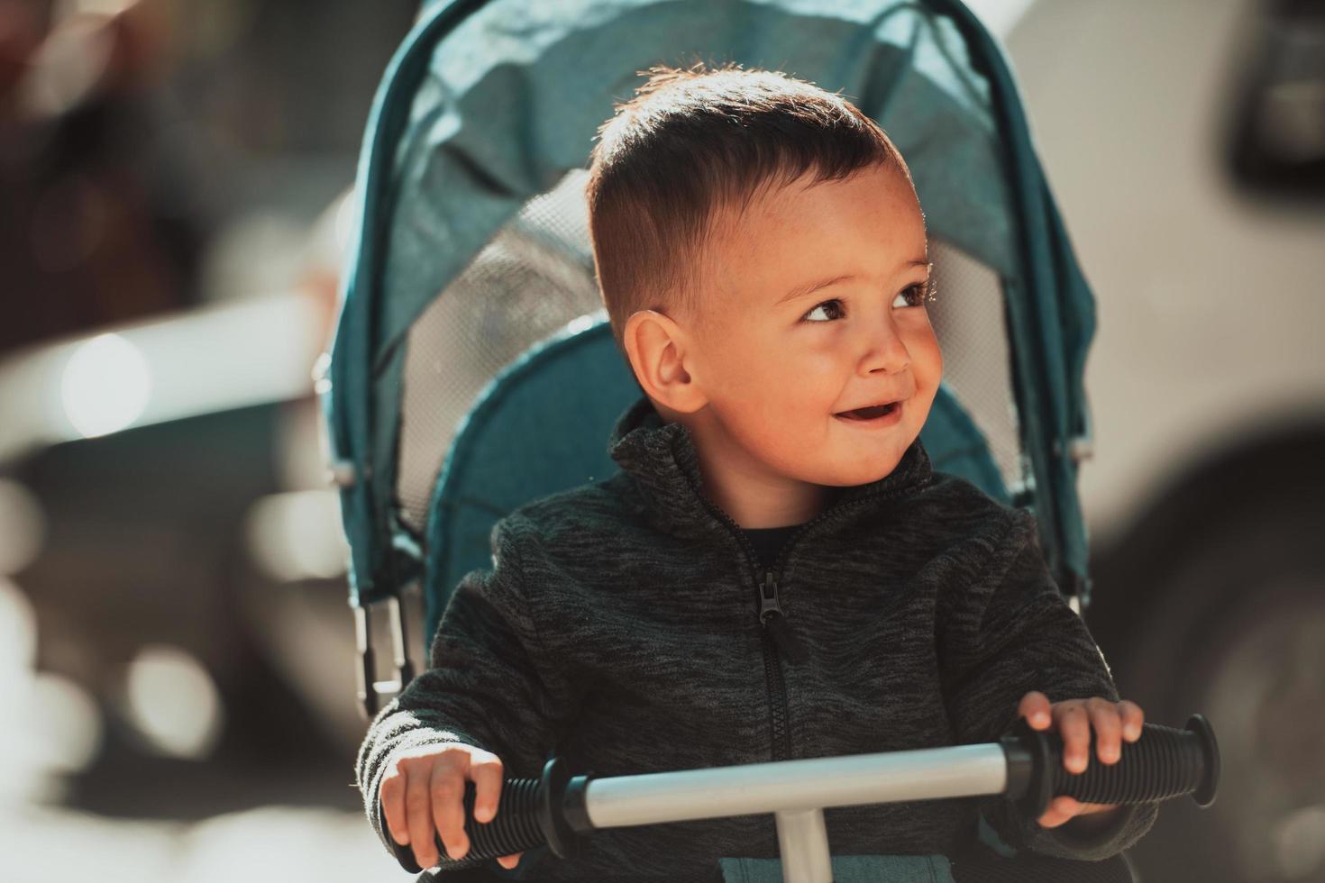 Sweet baby boy in a stroller bicycle outdoors. Little child in a pram. Infant kid in a pushchair. Spring walks with kids. photo