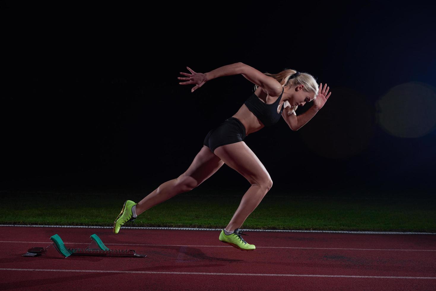 woman  sprinter leaving starting blocks photo