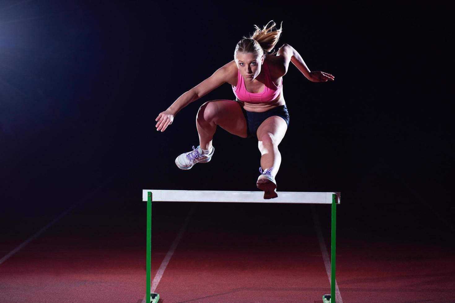 mujer atleta saltando sobre obstáculos foto