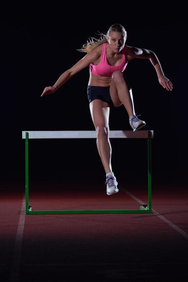 woman athlete jumping over a hurdles photo