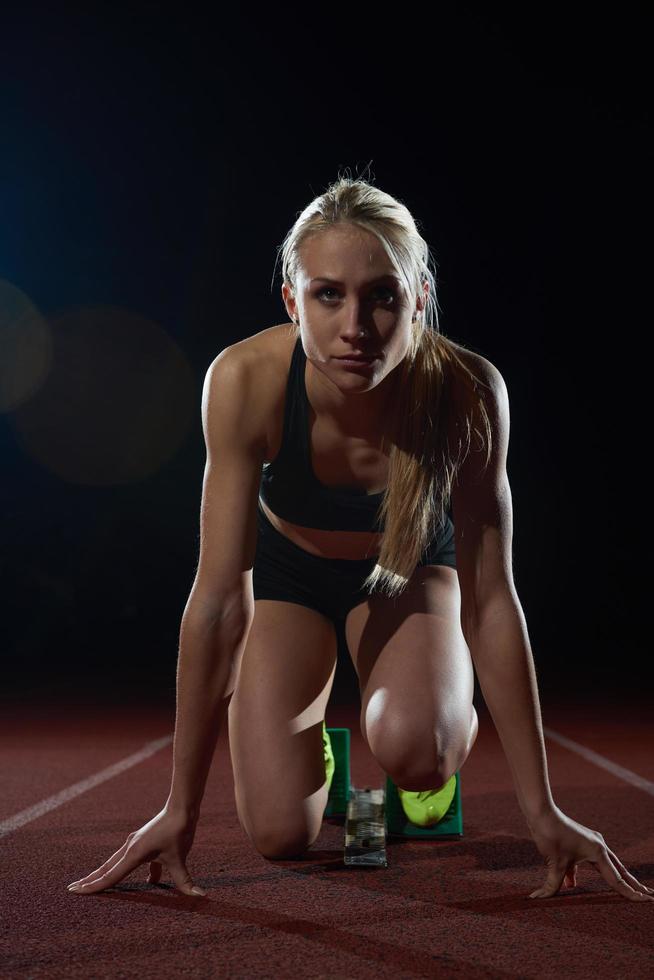 woman  sprinter leaving starting blocks photo