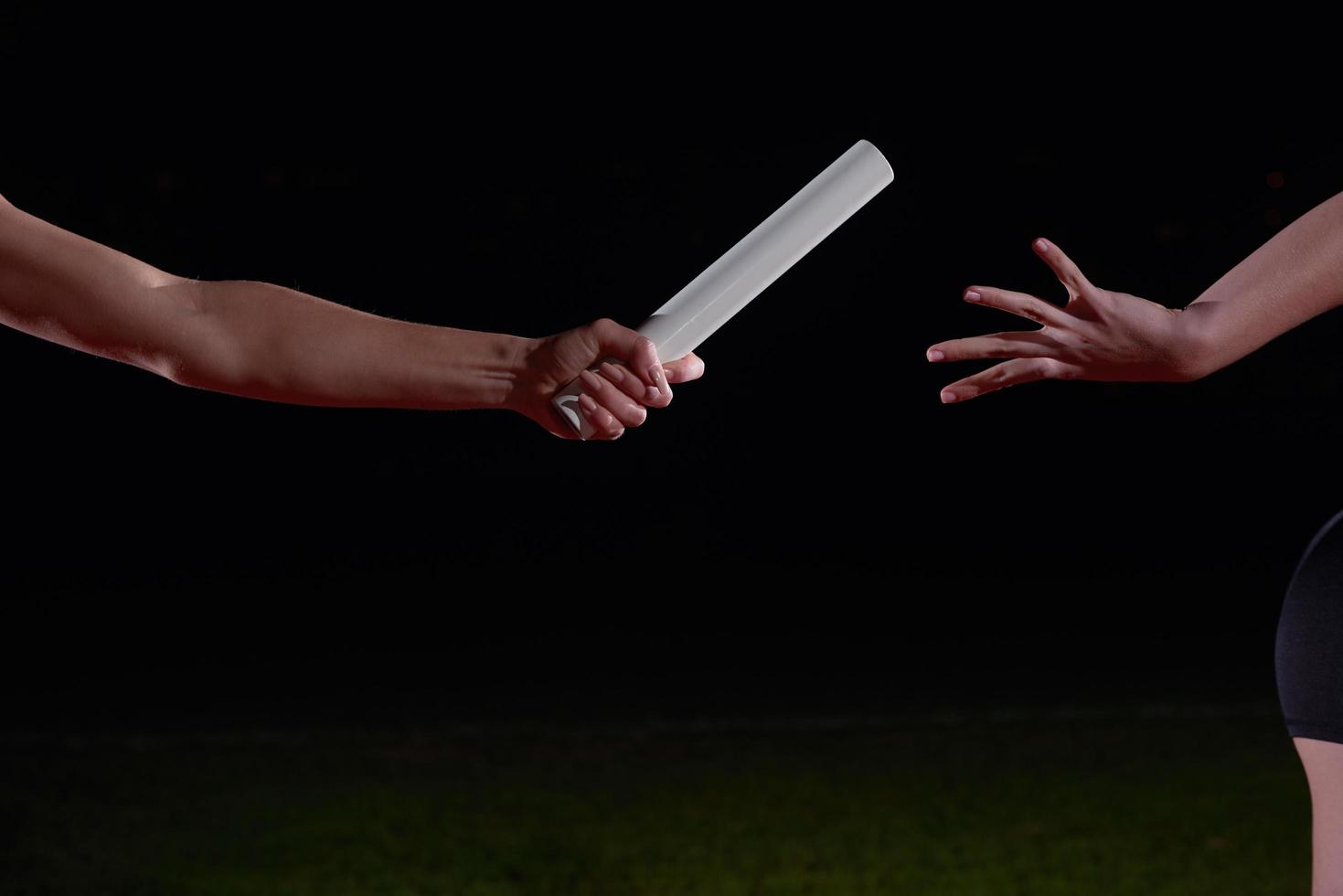 athletic runners passing baton in relay race photo