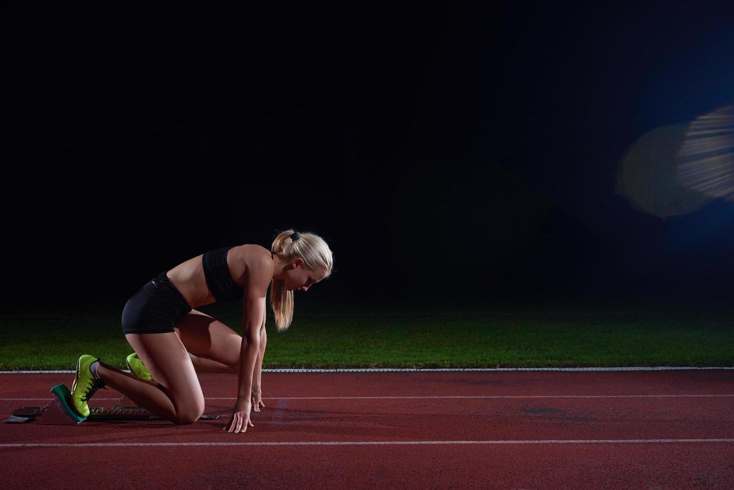 woman  sprinter leaving starting blocks photo