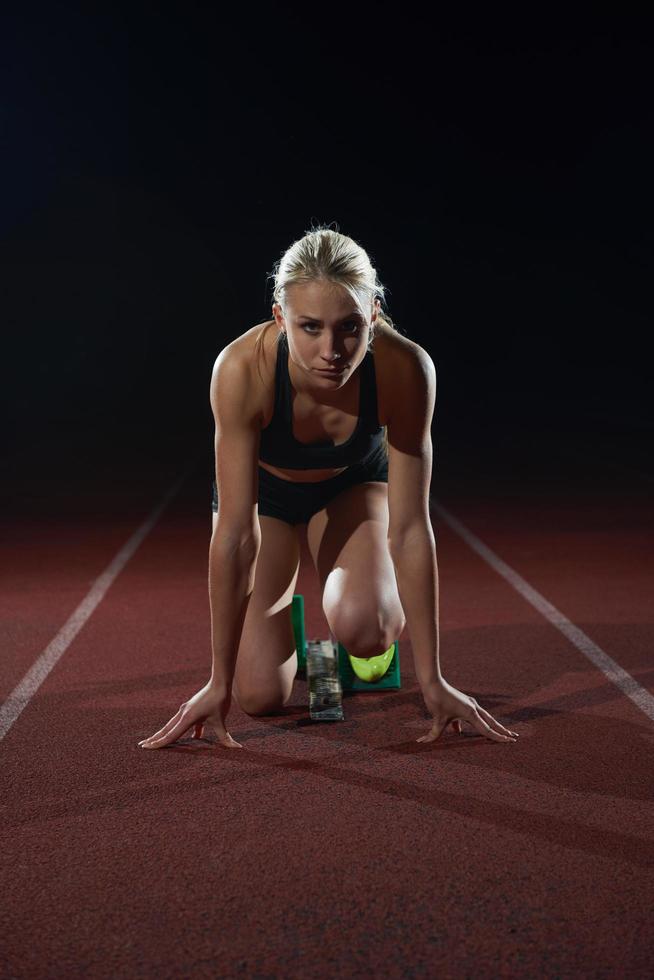 woman  sprinter leaving starting blocks photo