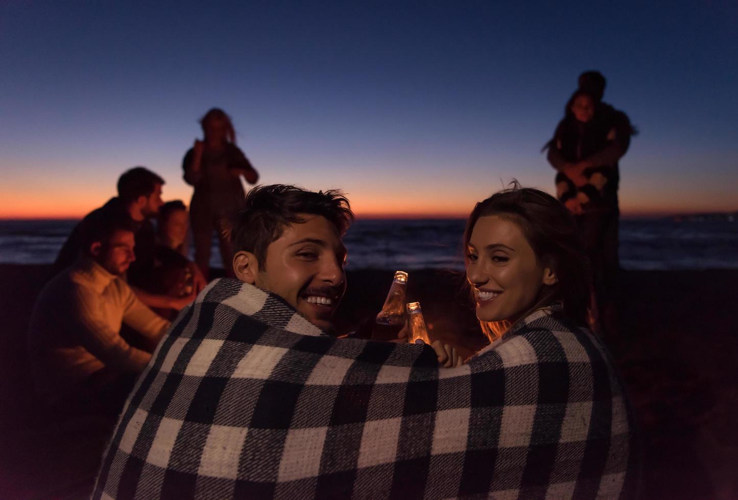 Couple enjoying with friends at sunset on the beach photo