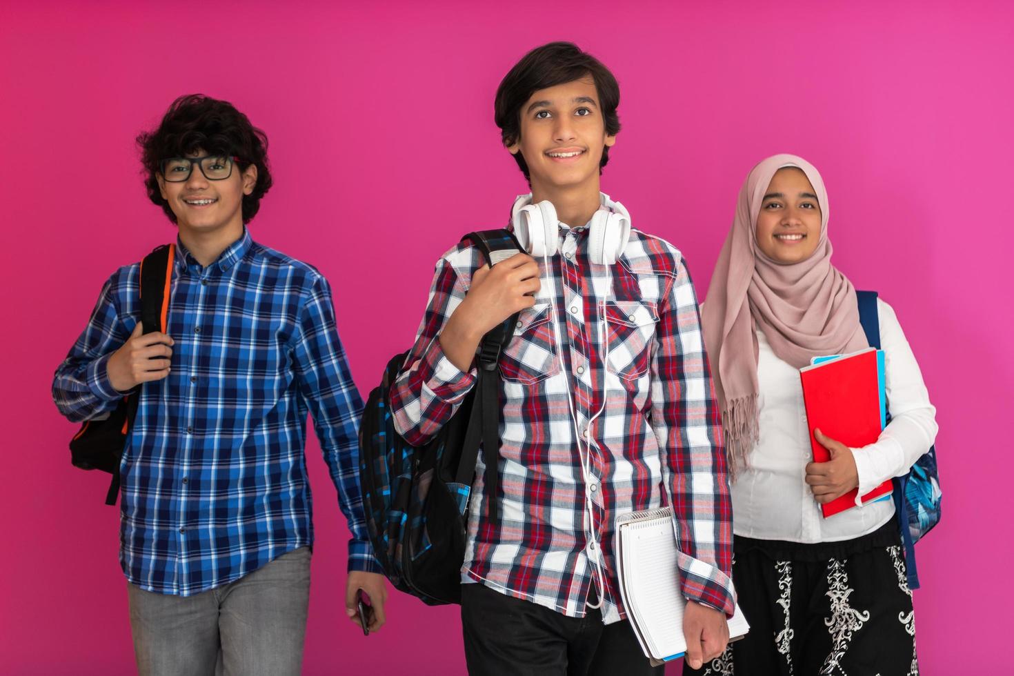 A group of Arab teenagers, a student team walking forward into the future and back to school the concept of a pink background. The concept of successful education for young people. Selective focus photo