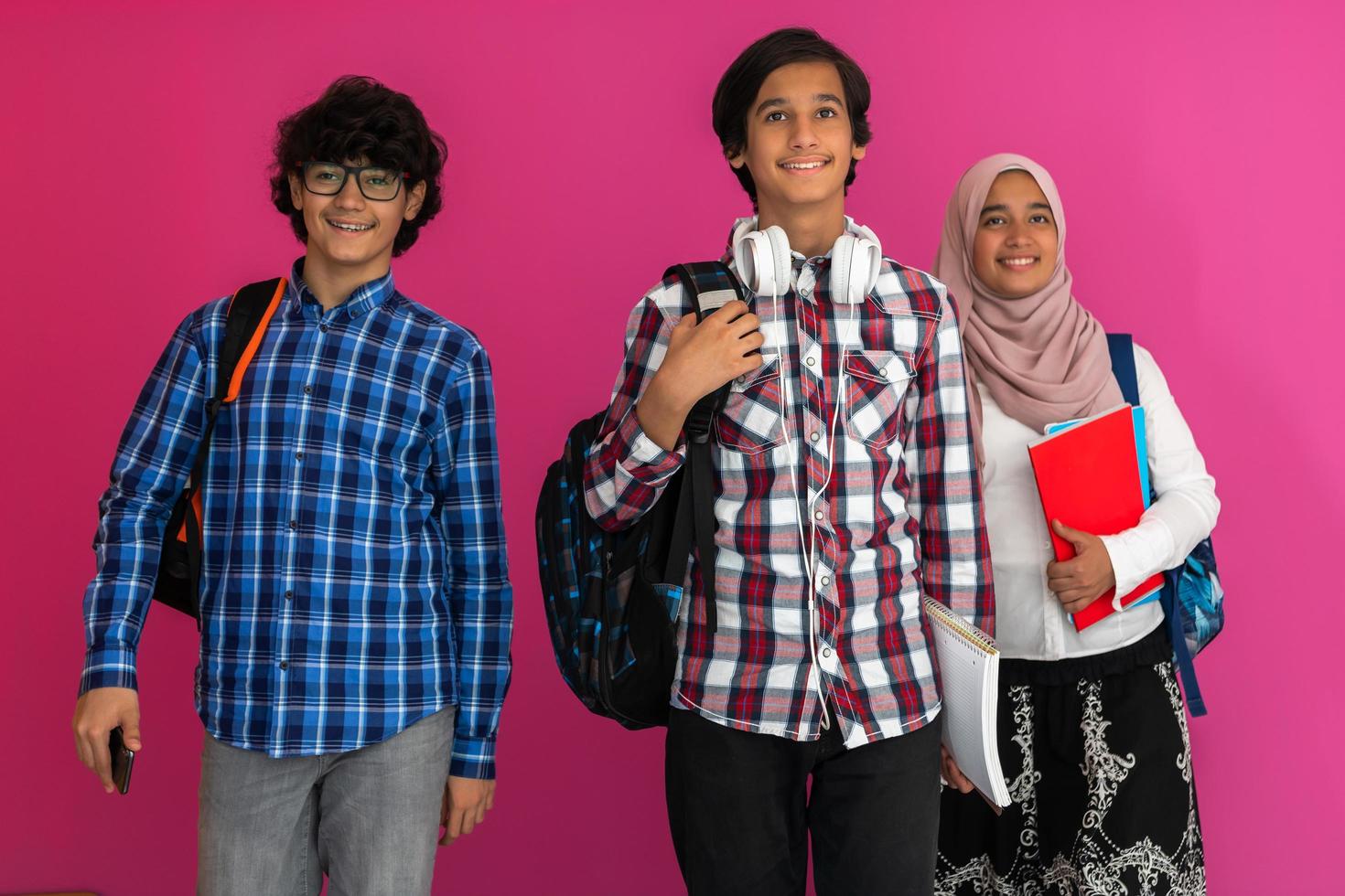 A group of Arab teenagers, a student team walking forward into the future and back to school the concept of a pink background. The concept of successful education for young people. Selective focus photo