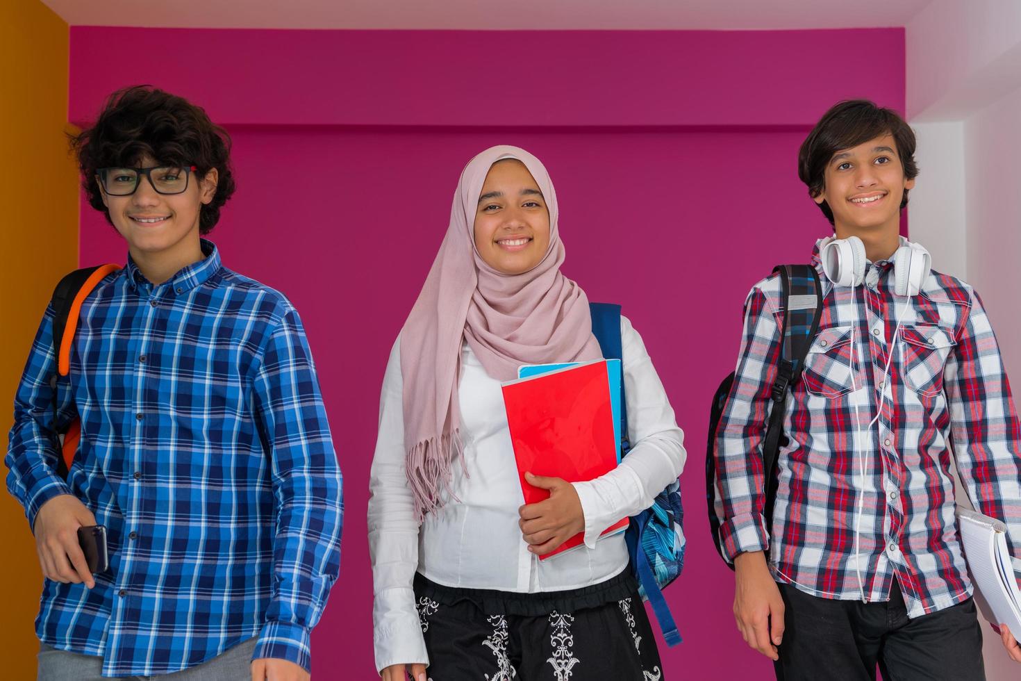 A group of Arab teenagers, a student team walking forward into the future and back to school the concept of a pink background. The concept of successful education for young people. Selective focus photo