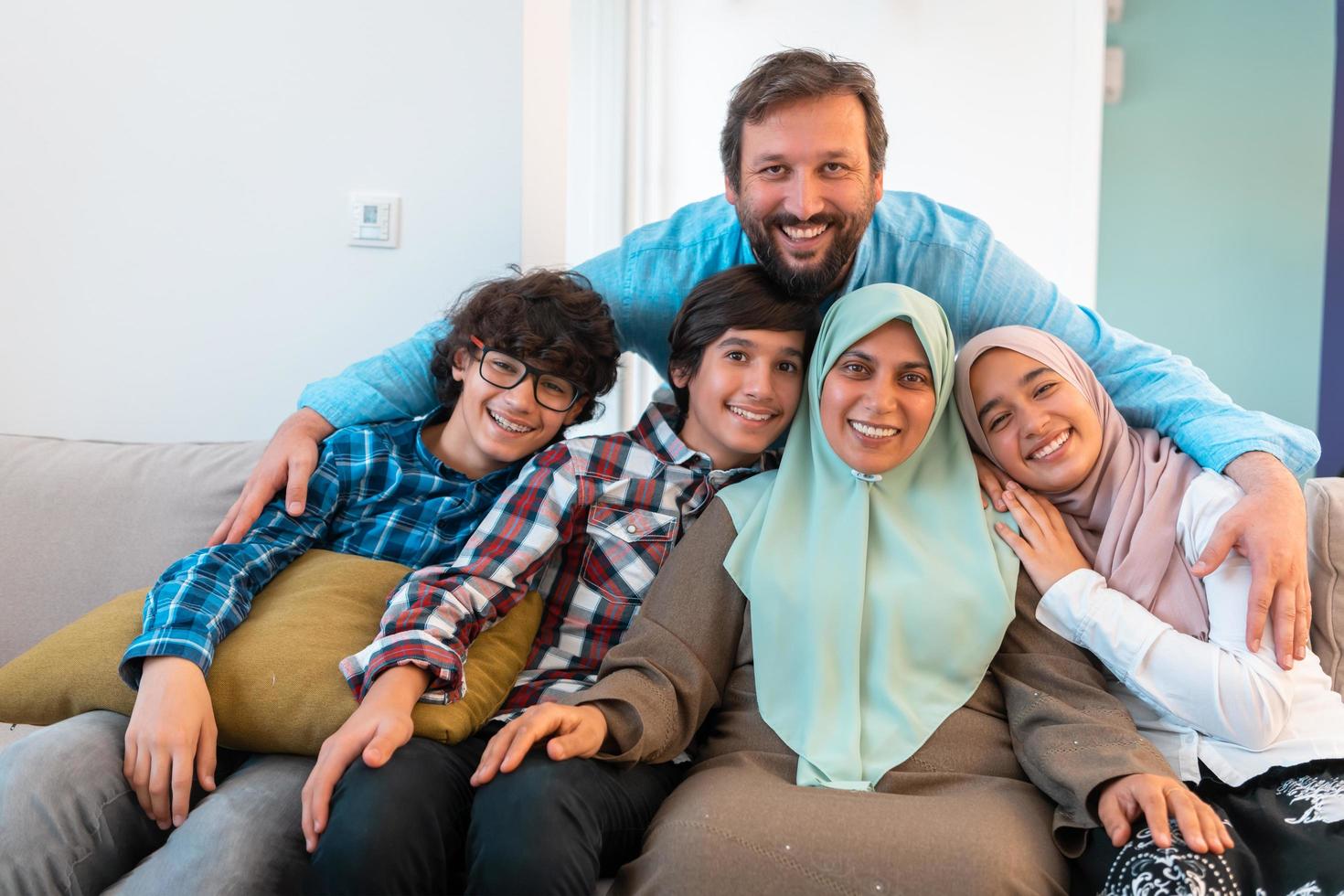 Portrait photo of an arab muslim family sitting on a couch in the living room of a large modern house. Selective focus