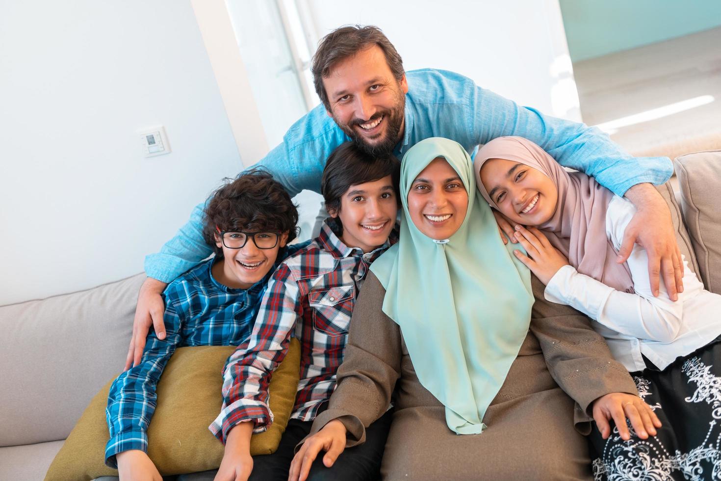 Portrait photo of an arab muslim family sitting on a couch in the living room of a large modern house. Selective focus