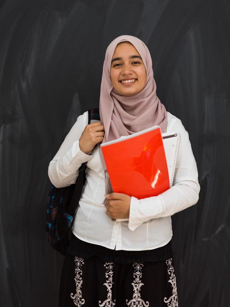 retrato de una feliz estudiante universitaria de oriente medio contra una pizarra negra en el aula foto