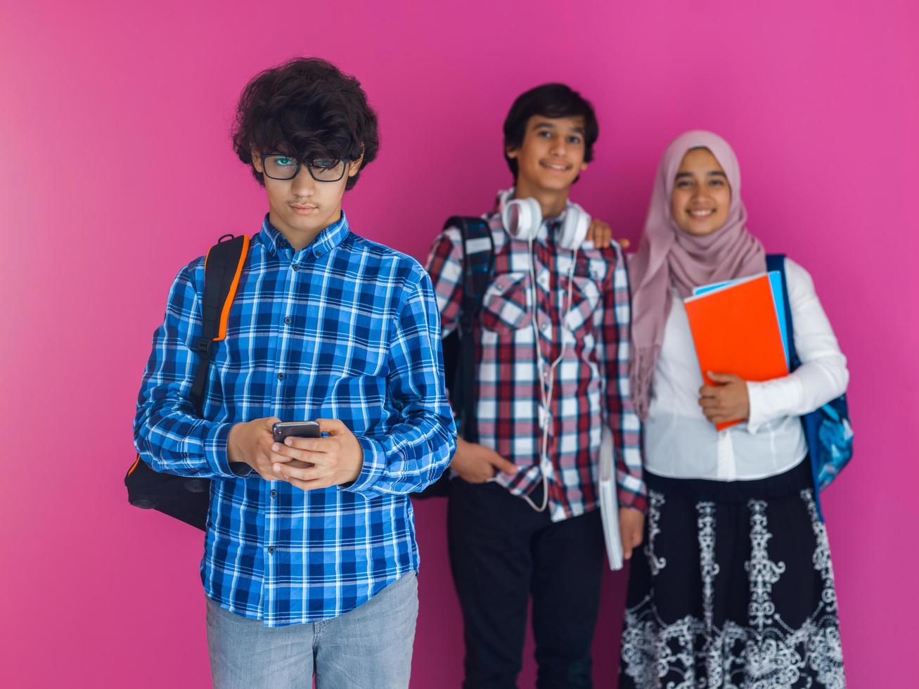 A group of Arab teenagers, a student team walking forward into the future and back to school the concept of a pink background. The concept of successful education for young people. Selective focus photo