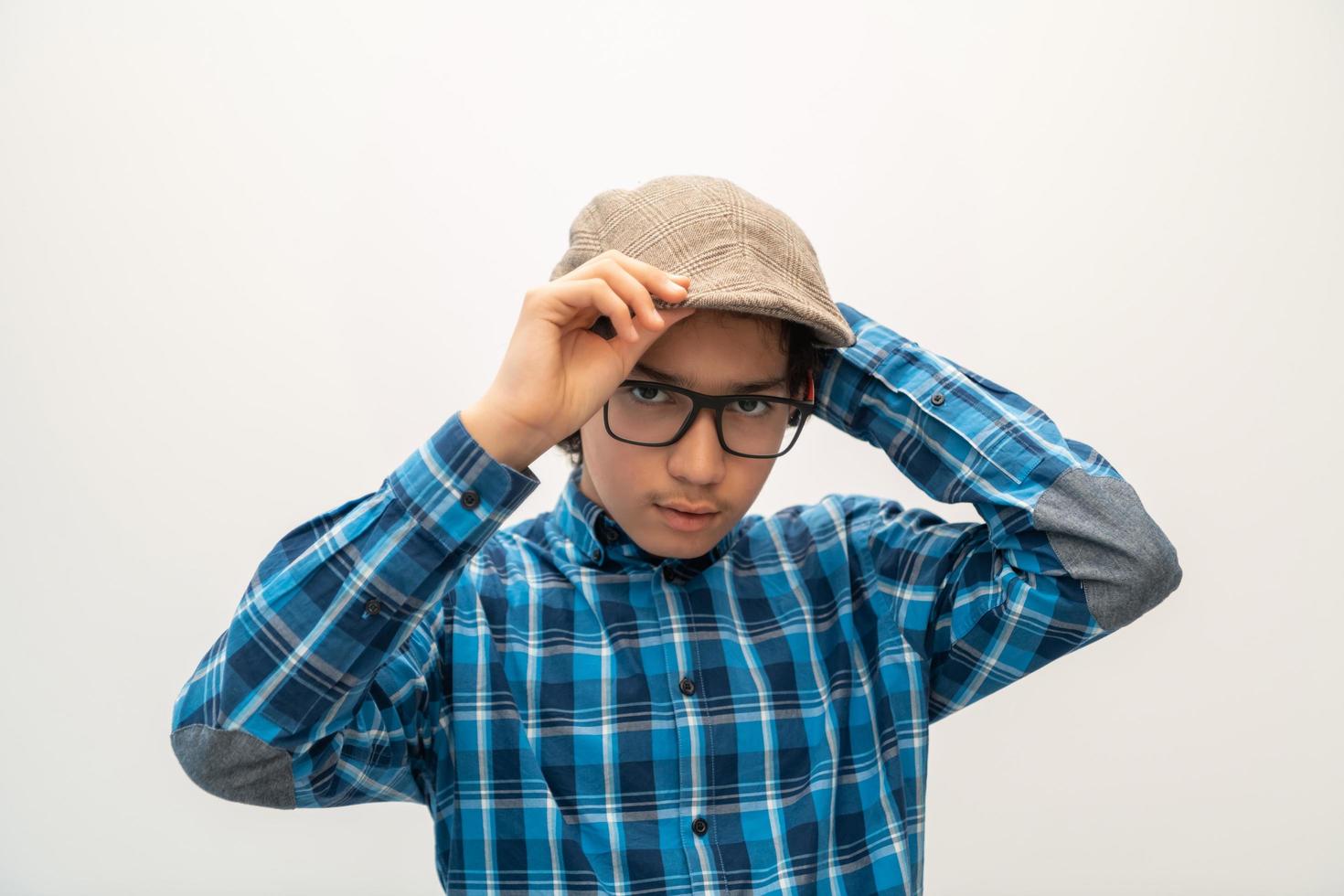retrato de un adolescente árabe de aspecto inteligente con gafas que lleva un sombrero en un aspecto informal de la escuela aislado en un espacio de copia en blanco foto