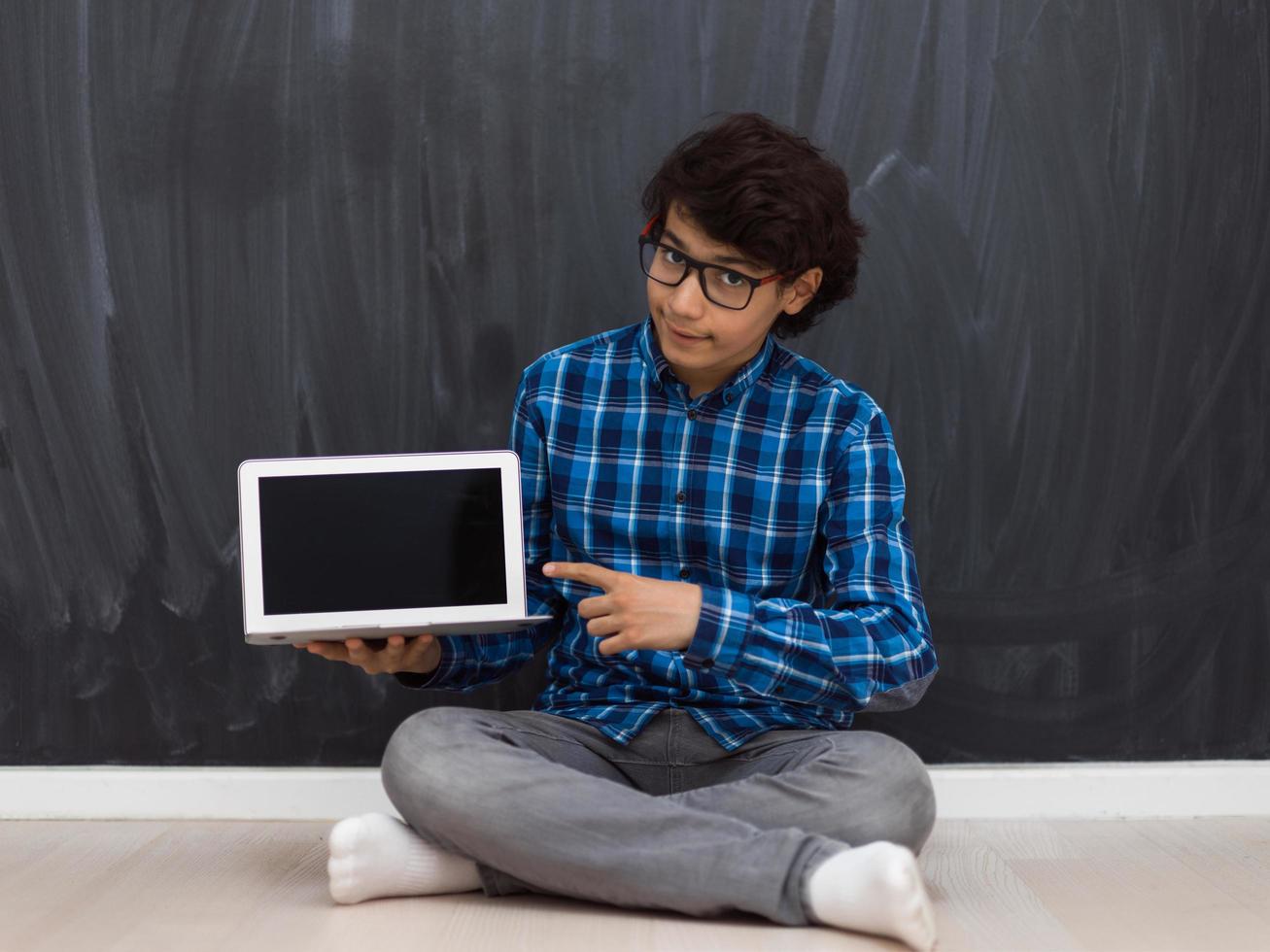 Arab teenager using laptop to work on homework and watch online education while staying at home cause coronavirus pandemic quarantine photo