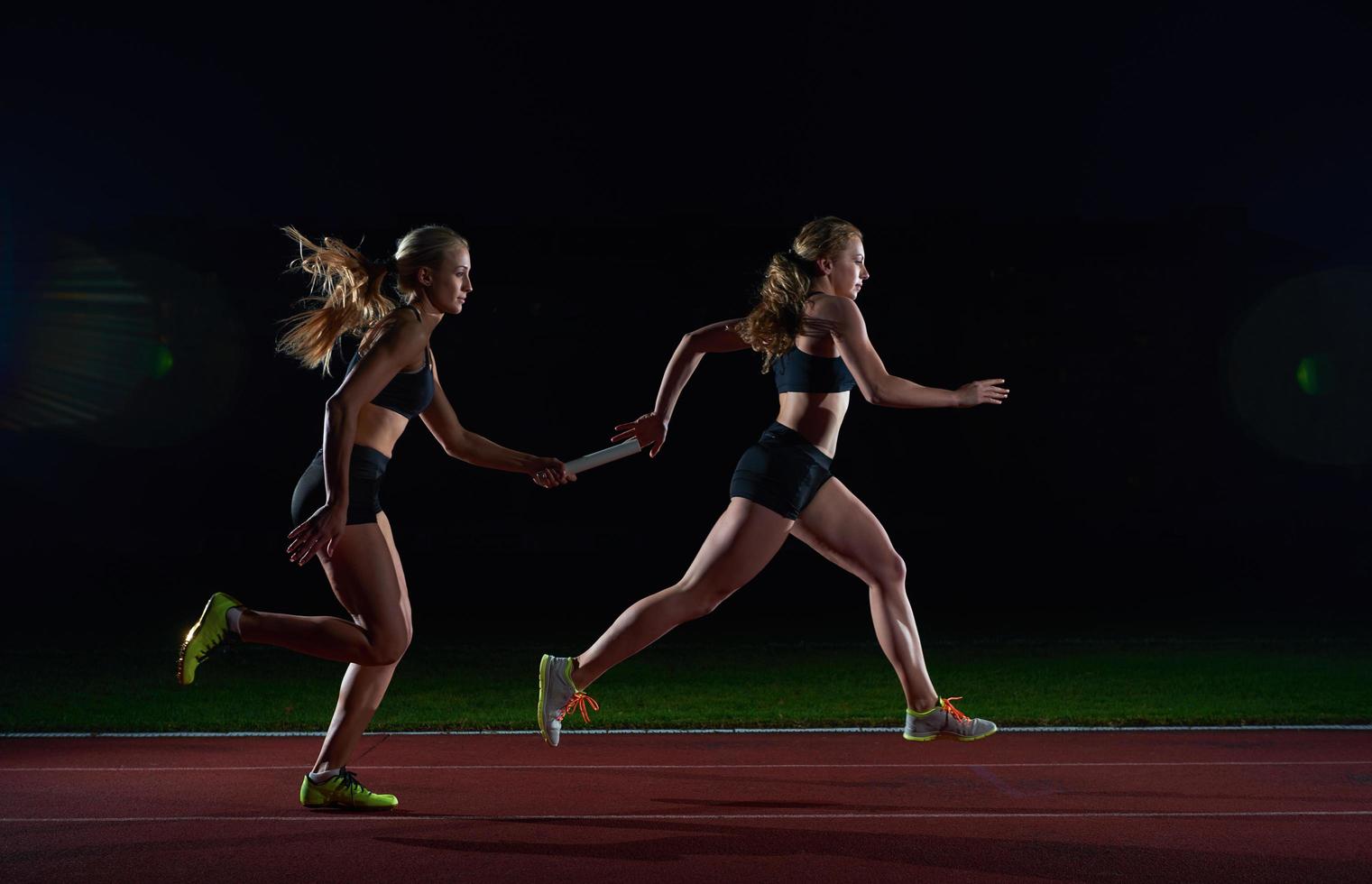 athletic runners passing baton in relay race photo