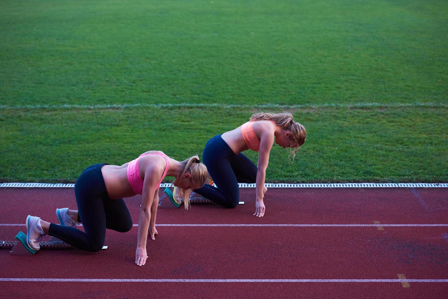 woman group  running on athletics race track from start photo