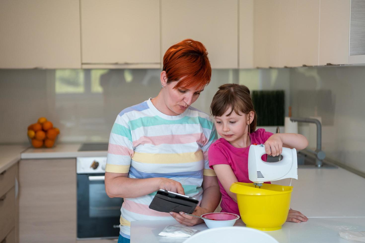 little girl and mom making tastz cake in kithen family having fun at home photo