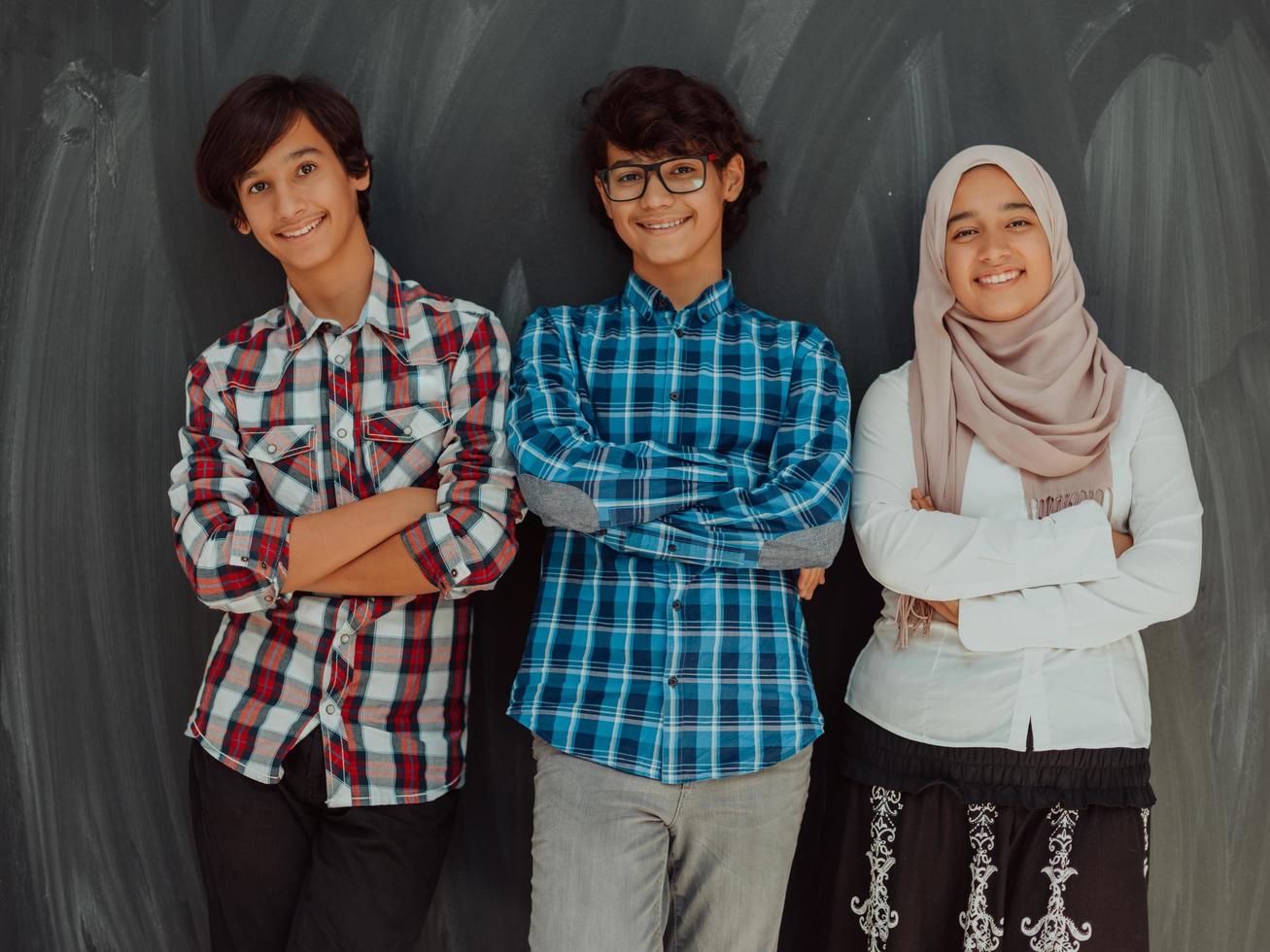 A portrait of a group of Arab teenagers with crossed arms standing in front of a school board . The concept of modern and successful education photo