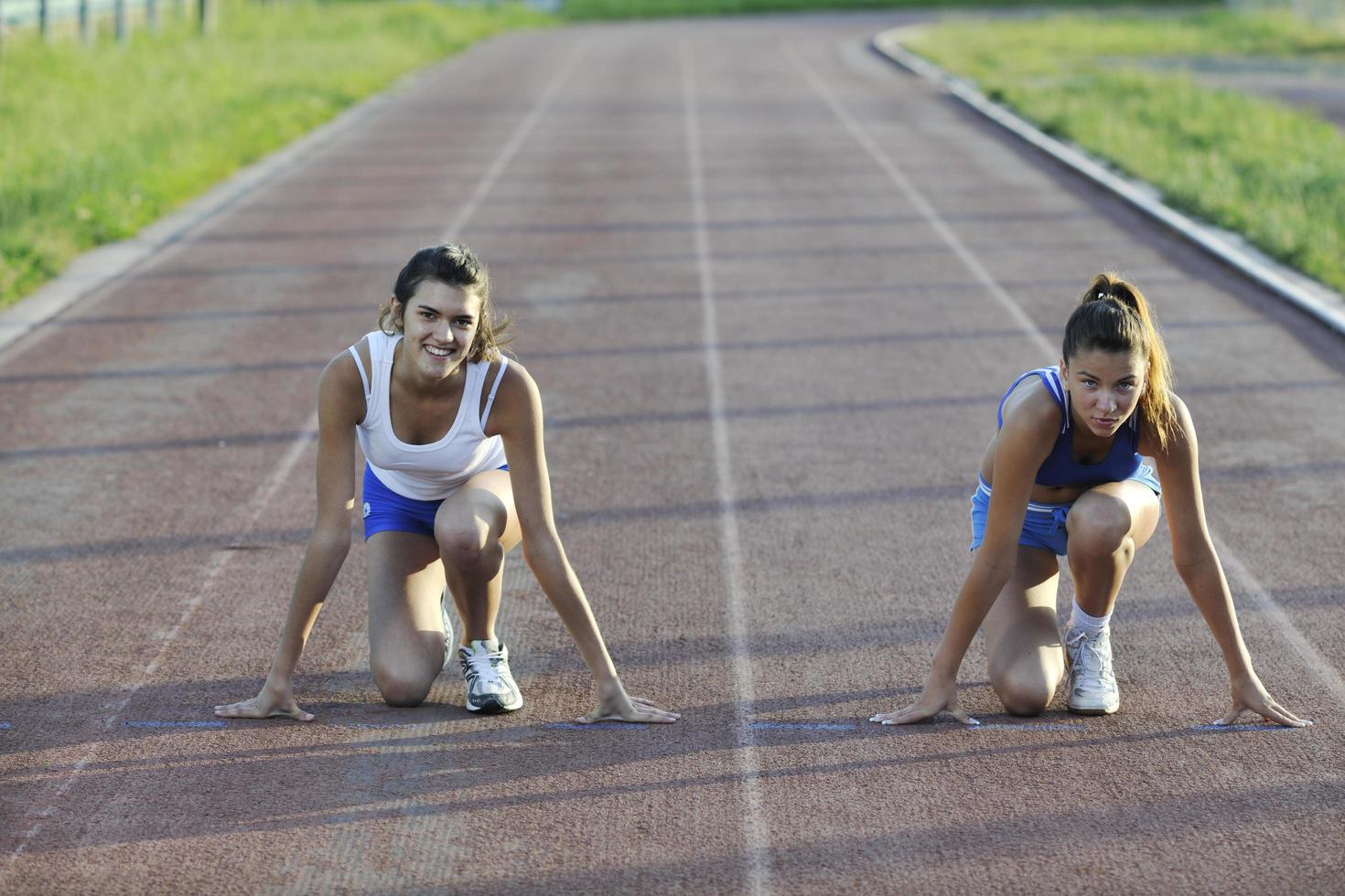 two girls running on athletic race track photo