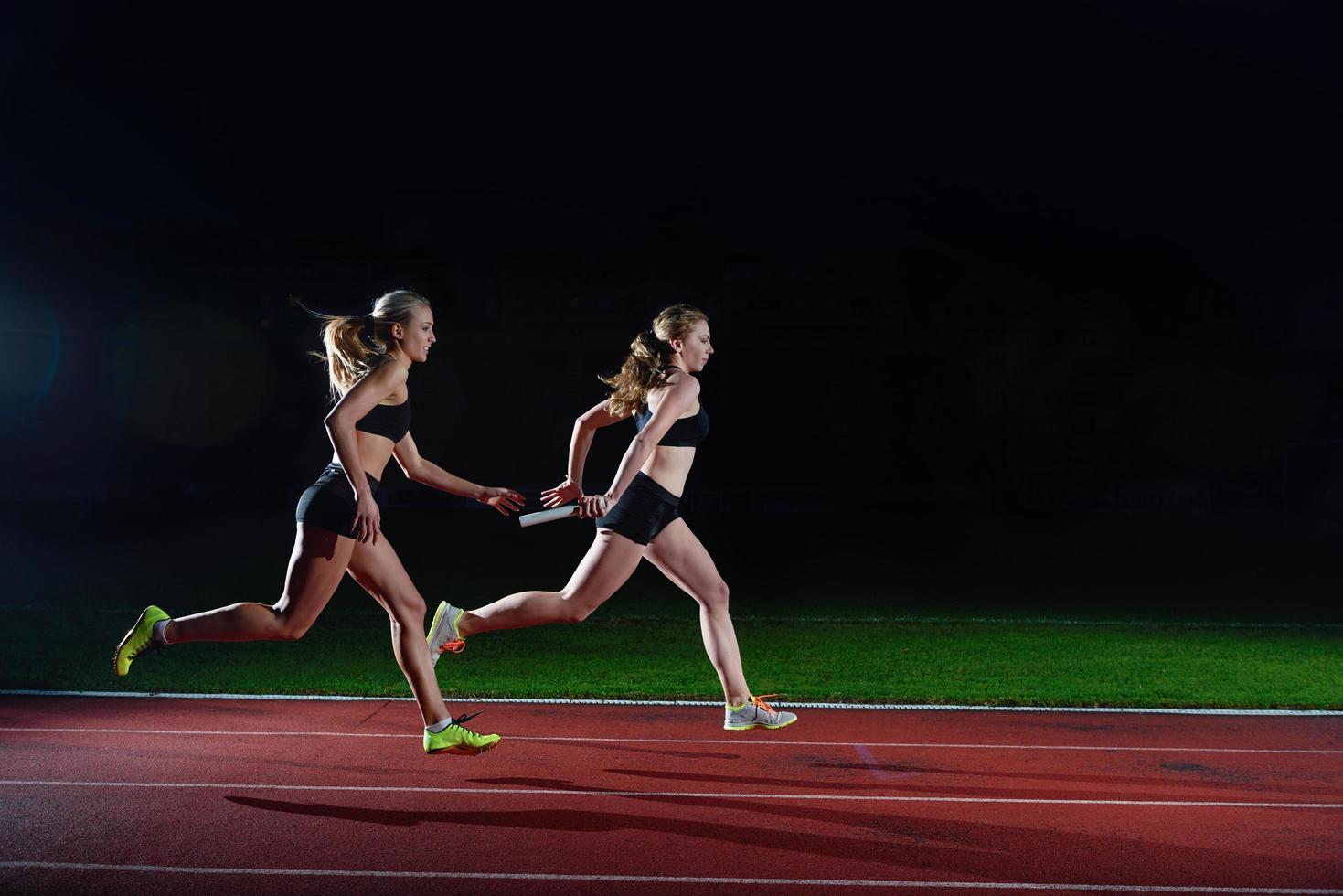 athletic runners passing baton in relay race photo