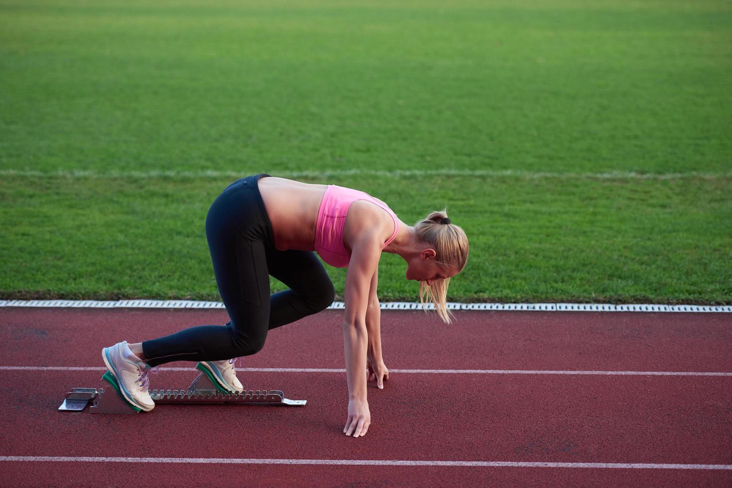 woman  sprinter leaving starting blocks photo