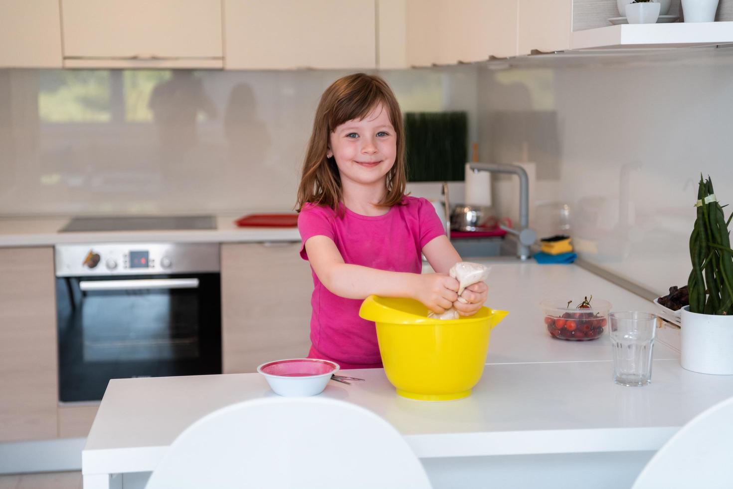 la niña prepara masa en una batidora sumergible y se lame los dedos. los electrodomésticos modernos son convenientes y simples incluso para los niños. un pasatiempo de cocinar. enfoque selectivo foto