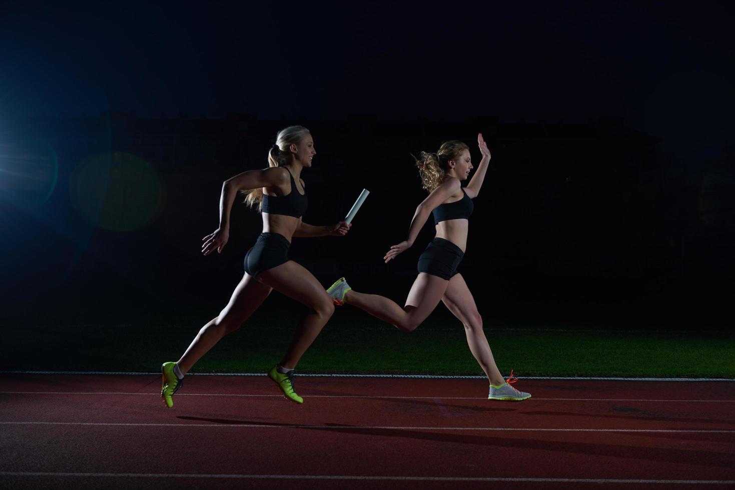 athletic runners passing baton in relay race photo