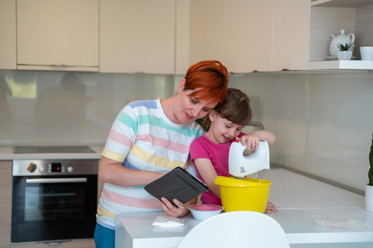 little girl and mom making tastz cake in kithen family having fun at home photo
