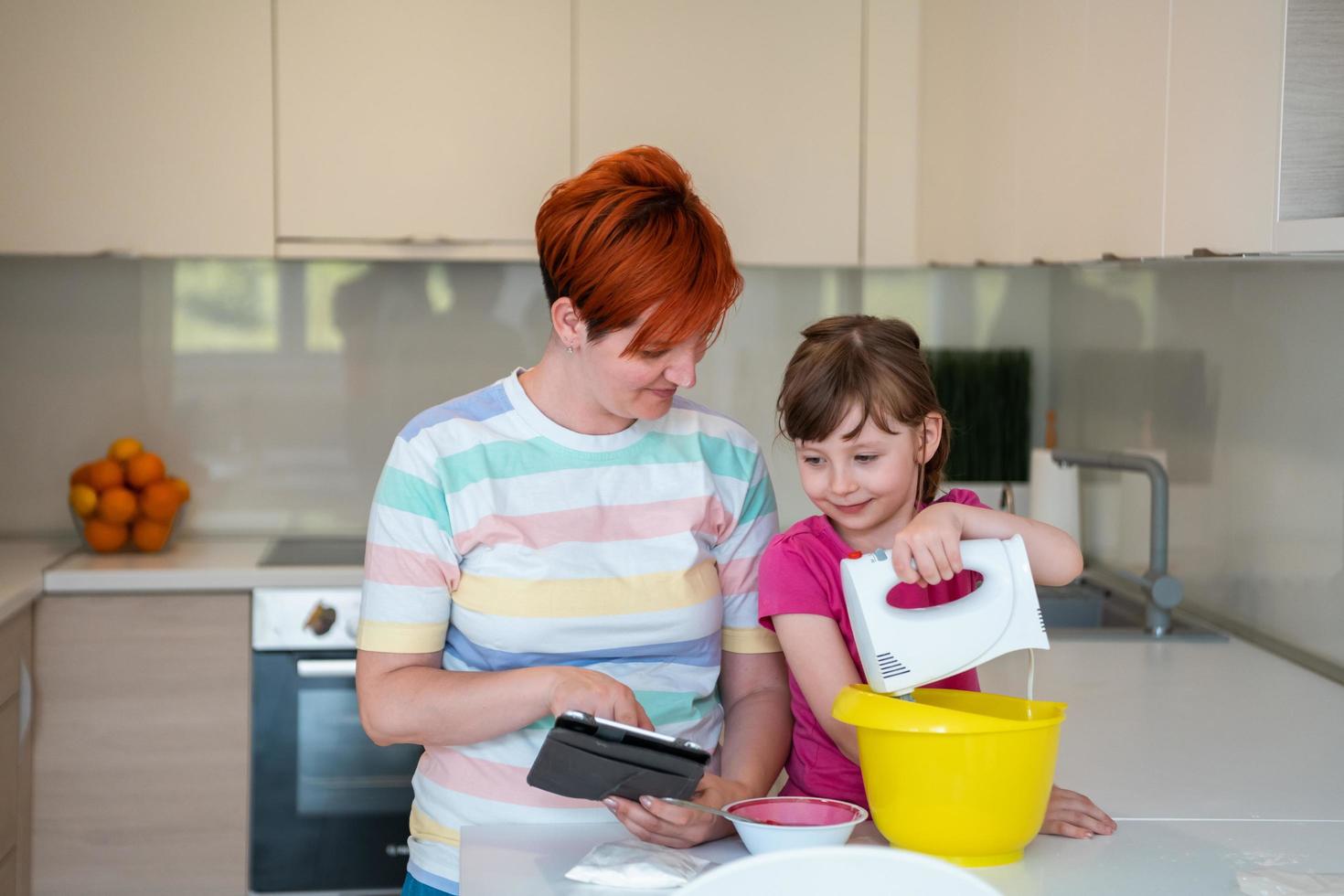 little girl and mom making tastz cake in kithen family having fun at home photo