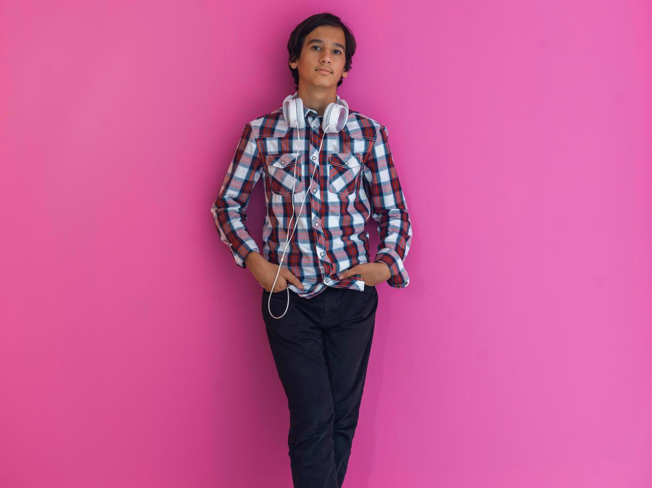 Arabic Teenage Boy Wearing Headphones And Listening To Music pink background photo