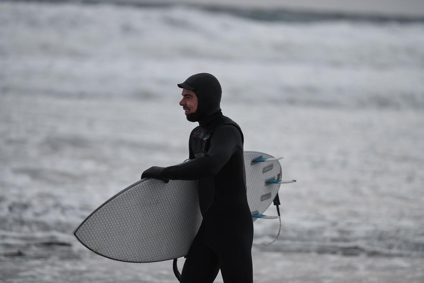 surfista ártico yendo por la playa después de surfear foto