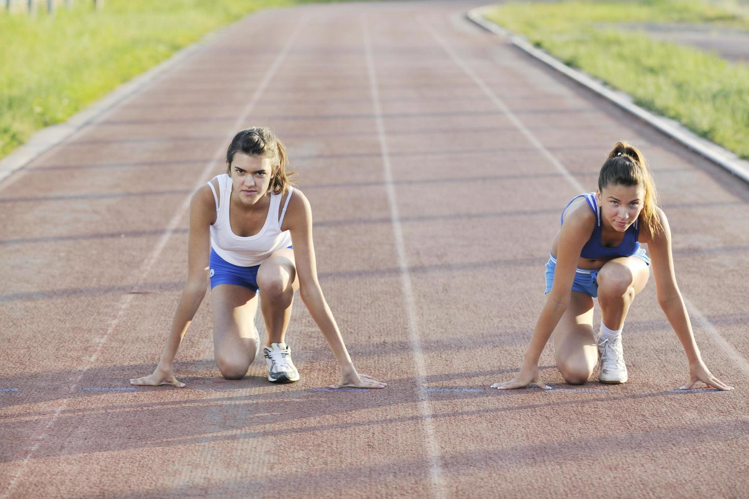 two girls running on athletic race track photo